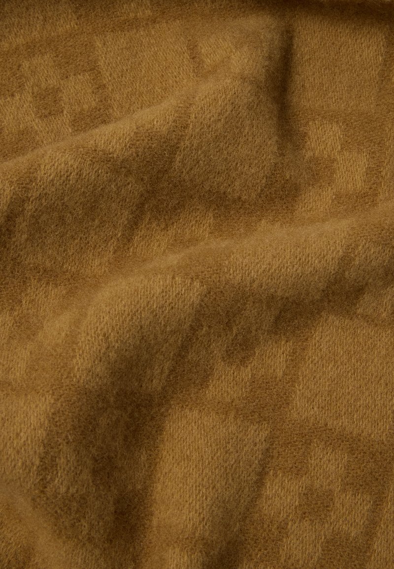 Tan wool blanket featuring a soft, textured surface with a subtle geometric pattern. The fabric appears warm and inviting.