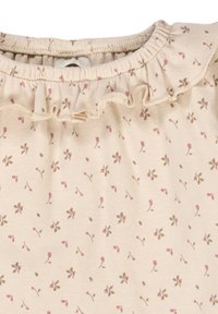 Weicher beiger Stoff mit kleinen rosa und braunen Blumendrucken und einem gerafften Rüschendetail entlang des Ausschnitts.