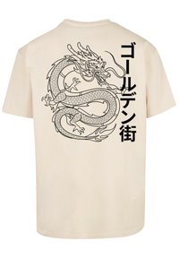 Beige T-Shirt mit einem detaillierten schwarzen Drachenmotiv auf dem Rücken und auffälligem japanischem Text an der Seite. Aus Baumwollstoff, mit normaler Passform.
