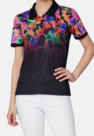 Poloshirt met korte mouwen, zwarte kraag en mouwen, kleurrijk abstract bloemenpatroon op het bovenste deel, gedragen met een witte broek.