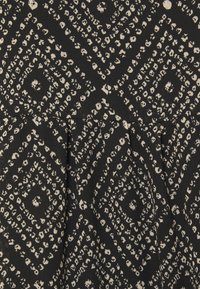 Tissu noir avec un motif abstrait en pointillés blancs formant des losanges et des plis subtils créant une texture.