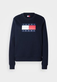 Felpa blu navy con collo a giro, polsini e orlo a coste, caratterizzata da un logo Tommy Jeans bianco e rosso sul petto.