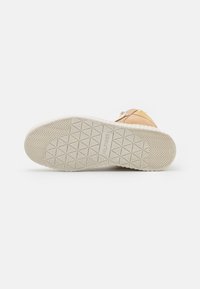 Stivaletto beige con suola in gomma bianca che mostra un motivo geometrico e il logo "HILFIGER" sul fondo.