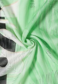 Tissu vert clair avec motifs floraux noirs et blancs et accents argentés ponctués torsadés en spirale.