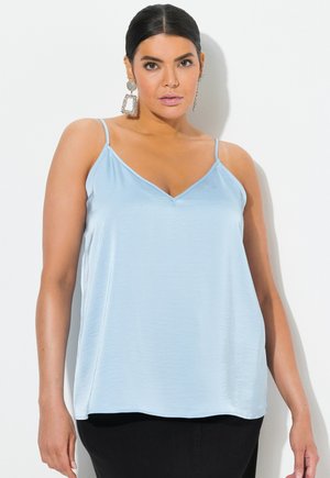 Lysblå satin camisole med tynde stropper, V-halsudskæring og en afslappet pasform, parret med mørke bukser og statement øreringe.