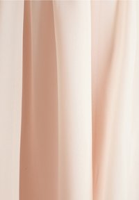 Lichtroze stof valt elegant en heeft een zachte, doorschijnende textuur. Het materiaal lijkt lichtgewicht en glad, met een delicate, vloeiende kwaliteit.