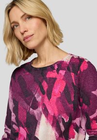 Lila und rosa gemusterter Strickpullover mit abstrakten Pinselstrichen, Rundhalsausschnitt und dezenten Glitzerdetails.