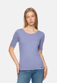 Helllila eng anliegendes T-Shirt mit kurzen Ärmeln, Rundhalsausschnitt und minimalistischem schwarzen Logodetail am Saum. Glatte Textur und dehnbare Stoffqualität.