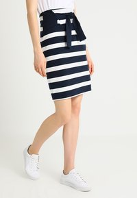 Námořnická a bílá pruhovaná tužková sukně s páskem na zavázání. Vyrobena z elastického materiálu, s přiléhavým střihem a hladkým povrchem.