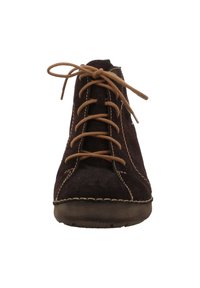 Chaussure en suede marron foncé à lacets avec un bout arrondi, des coutures contrastantes légères et une semelle en caoutchouc texturée. Les lacets sont noués en un nœud.