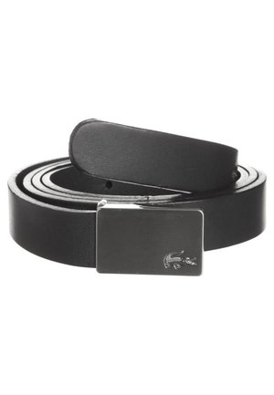 Ceinture en cuir noir enroulée avec une boucle rectangulaire en argent ornée d'un logo de crocodile en relief sur fond blanc.