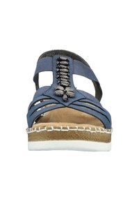 Niebieskie sandały z tkaniny, z krzyżującymi się paskami, ozdobnym czarnym okuciem z przodu oraz naturalnym środkowym podłożem z juty. Białe przeszycia akcentują podeszwę.