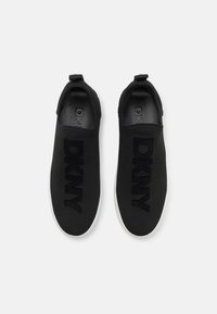 Mustad musta värvi slip-on spordijalatsid DKNY logo on silmapaistvalt esile tõstetud, valmistatud kudumismaterjalist, millel on sile, kontrastse valge tallaga.