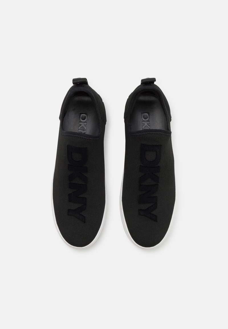 Baskets noires à enfiler avec le logo DKNY bien en vue, fabriquées en matériau tricoté, dotées d'une semelle lisse en blanc contrastant.