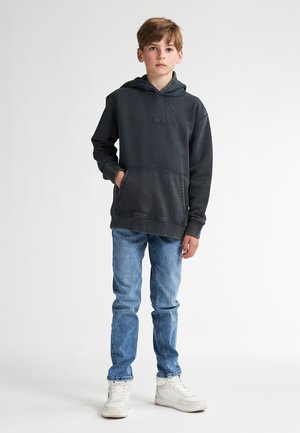 Donkergrijze hoodie met een voorzak, ribbels aan de mouwen en onderkant; gecombineerd met lichtblauwe jeans en witte sneakers. Glad materiaal, casual ontwerp.