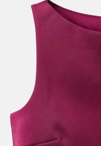 Top sin mangas en un magenta profundo, hecho de una tela suave. Presenta un escote redondeado y costuras sutiles para una silueta ajustada.