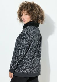 Pull di pile grigio con motivo floreale nero, dotato di un colletto di pelliccia nera e maniche lunghe, progettato per comfort e calore.