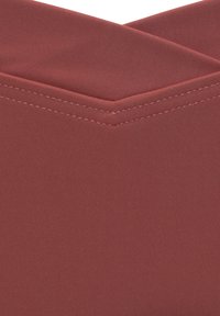 Rode ribbelstof met een gladde textuur, die aan de bovenkant een V-vorm vormt en nauwkeurige stiksels langs de randen tentoonstelt.