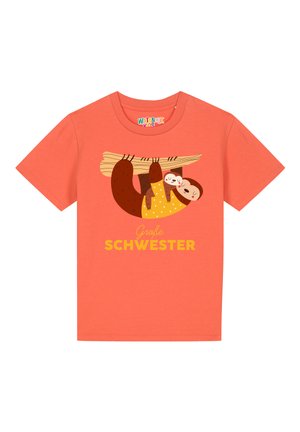 Koraal katoen t-shirt met een illustratie van een luiaard die aan een tak hangt, met de tekst "Große Schwester" in het geel eronder. Korte mouwen.