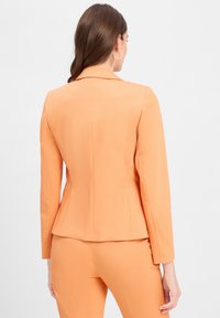 Orange maßgeschneiderte Blazer, strukturiertes Design, lange Ärmel, Reverskragen, glatte Textur, taillierte Silhouette und Rückennahtdetails.