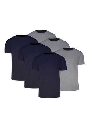 Mann trägt ein einfaches graues T-Shirt mit kurzen Ärmeln und eng anliegende schwarze Boxershorts, steht vor weißem Hintergrund.