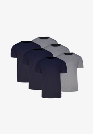 Mann trägt ein einfaches graues T-Shirt mit kurzen Ärmeln und eng anliegende schwarze Boxershorts, steht vor weißem Hintergrund.