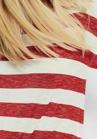 T-shirt à manches courtes rayé rouge et blanc avec une coupe décontractée. Le tissu semble léger et légèrement texturé, montrant un tricot visible.