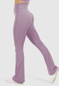 Hoog-waist, flared leggings van zachte lavendelkleurige stof, met een soepele textuur en schone naden, gecombineerd met witte sportieve schoenen.