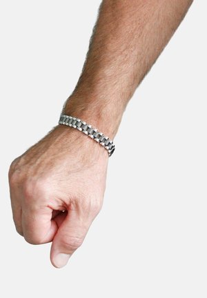 Adult male arm with clenched fist wearing a silver metal link bracelet against a plain light background.
