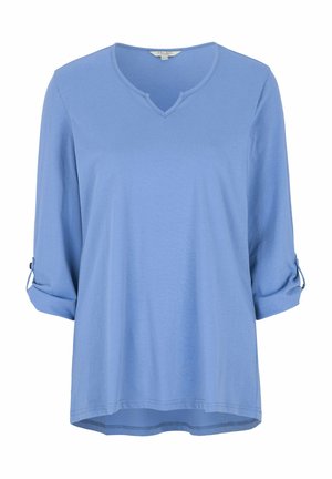 Lyseblå langærmet bluse i blødt materiale med V-hals, opkrøllede ærmer der er fastgjort med knapper, og en let længere bagkant.