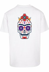 Hvit bomull t-skjorte med et fargerikt pixel-kunst hodeskallemotiv på baksiden, prydet med blomsterdetaljer og intrikate detaljer.