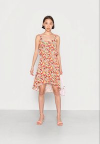 Vestido floral em laranja, rosa e verde com uma bainha assimétrica e ampla. Feito de um tecido leve, possui alças finas e um design franzido.