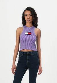 Lilla ribbet crop-top med høy hals har et merket lapp; sammen med m�ørke denimjeans. Jevn tekstur, tettsittende design.