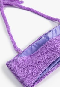 Bolso de mano morado con exterior fruncido, forro de satén suave y una larga correa trenzada. Presenta una superficie texturizada y arrugada para mayor detalle.