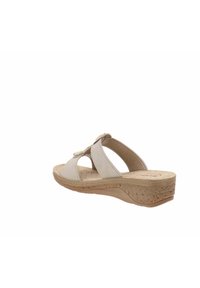 Sandali con zeppa beige dotati di una suola in sughero testurizzato, con cinturini incrociati e una parte superiore liscia. Il design include un accento decorativo sui cinturini.