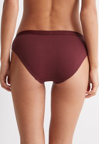 Burgunderfarbene Baumwoll-Hipster-Unterwäsche mit einem glatten Bund, genähten Nähten und mittlerer Abdeckung am Rücken. Weicher, elastischer Stoff.