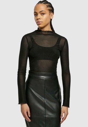 Haut noir à manches longues en tissu transparent avec un col rond, associé à une jupe noire en simili cuir taille haute au texture lisse.