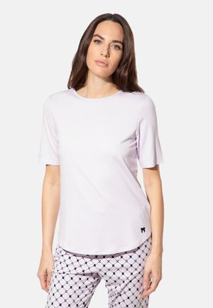 Hellblaues kurzärmliges T-Shirt mit Rundhalsausschnitt und einem schwarzen Logodetail am Saum, getragen mit gemusterten Schlafanzughosen.
