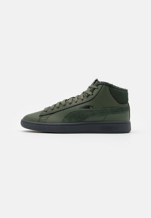 Sneaker Puma mid-top verde scuro con suola nera, lacci neri e logo, con dettaglio a striscia in suede e colletto imbottito intorno alla caviglia.