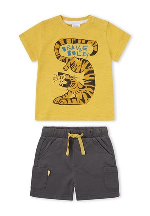 Camiseta amarilla para niño pequeño con tigre rugiente y texto "¡Valiente y audaz!" combinada con pantalones cortos gris oscuro con cordón amarillo y bolsillos.