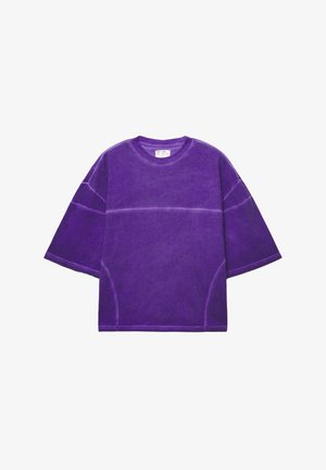 T-shirt viola oversize con maniche corte, realizzata in cotone, con una finitura testurizzata e dettagli di cucitura a contrasto.