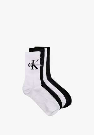 Tre paia di calzini da equipaggio in misto cotone: uno bianco con logo nero, uno bianco con strisce nere e uno completamente nero con logo.