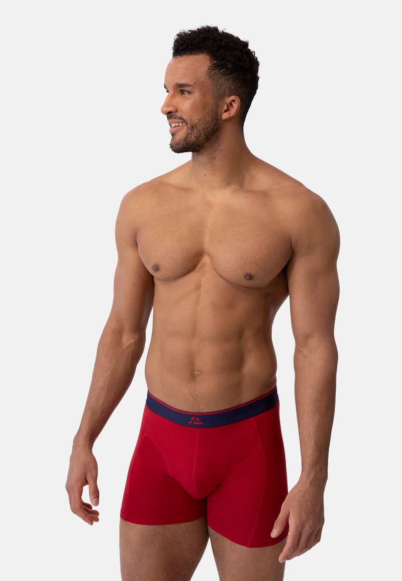 Rode boxershort met een marineblauwe tailleband, met een aansluitend ontwerp en een gladde textuur. De stof lijkt zacht en rekbaar.