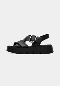 Black leather sandal with a thick platform sole, featuring an adjustable strap with a square metal buckle and cross-over design.