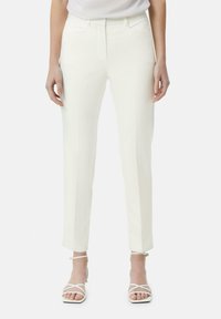 Witte op maat gemaakte broeken met een gladde textuur, voorzien van een recht model, zijzakken en subtiele naaddetails. Gepaard met witte sandalen met bandjes.