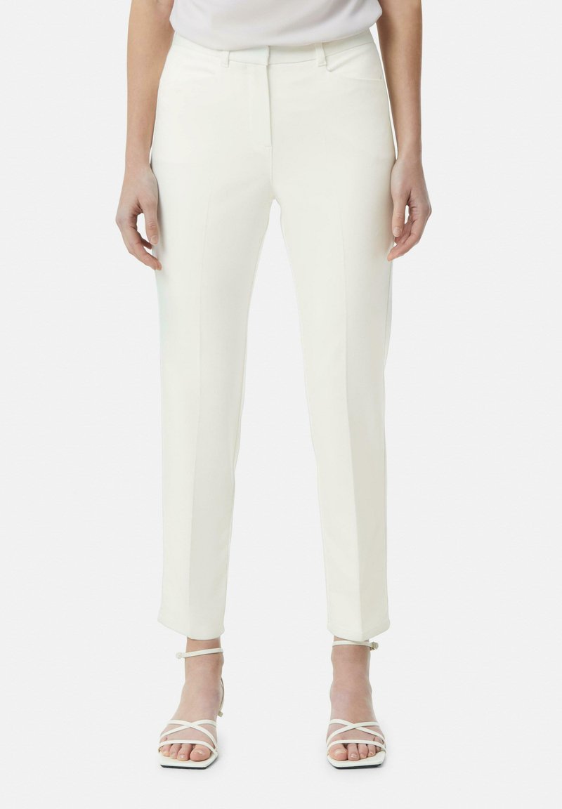 Witte op maat gemaakte broeken met een gladde textuur, voorzien van een recht model, zijzakken en subtiele naaddetails. Gepaard met witte sandalen met bandjes.