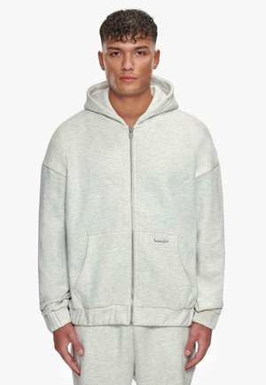 Gray zip-up hoodie made of soft fabric, featuring a front pocket, hood, and ribbed cuffs. Minimalistic design with a small logo accent.