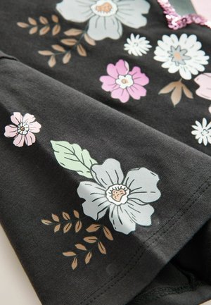 Svart tyg med ett blommönster som har ljusblå, rosa och vita blommor. Detaljer inkluderar gröna blad och beiga accenter.