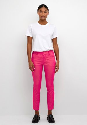 Roze aansluitende broek met voorzakken, rechte pijpdesign, gecombineerd met een witte crewneck t-shirt. Zwarte schoenen maken de look compleet.