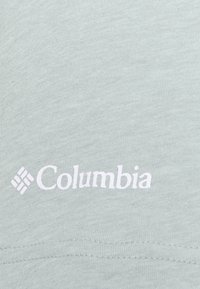 Tela de color gris claro con el logotipo de la marca Columbia impreso encima de la costura.